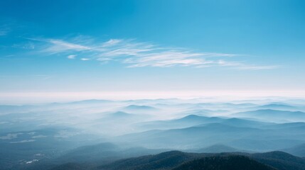Fototapeta premium Expansive view of majestic mountain peaks and serene blue sky with delicate clouds.