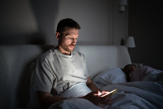 Tired sleepless man procrastinating at night using phone suffer from insomnia. Sleep disorder, night activity, web feed use, mental health stress, bedtime problem, anxious male late night screen time