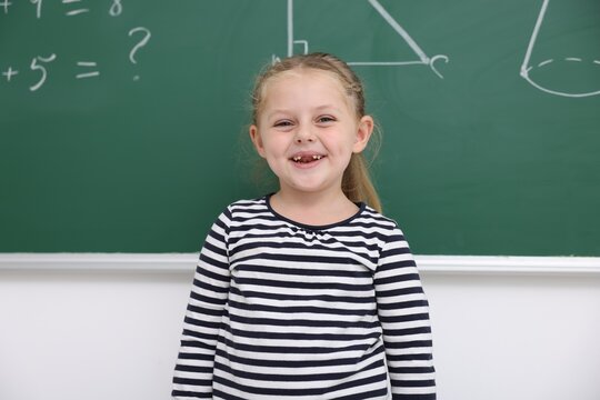 Portrait of smiling little girl near chalkboard in elementary school