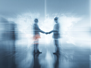 Two business professionals shake hands against a blurred world map, symbolizing partnership and global collaboration in a digital age.