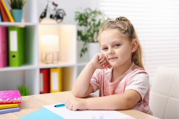 Naklejka premium Portrait of cute little girl at wooden desk during art lesson in elementary school
