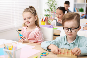 Fototapeta premium Cute children at wooden desks during lesson in elementary school