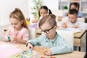 Fototapeta premium Cute children at wooden desks during lesson in elementary school