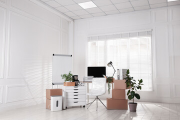 Moving day. Cardboard boxes, computer and furniture in office