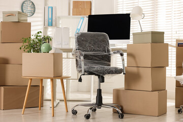Moving day. Cardboard boxes, computer and furniture in office