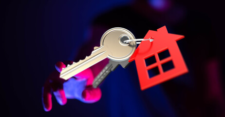 Person holding keys attached to a house shaped tag. Concept of new home ownership and real estate. Buy a home. Dream home. Key to success.
