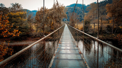 Suspension Bridge Stretching Over a River Through an Autumn Landscape. Salas, Asturias, Spain
