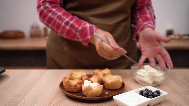 woman filling puff pastry tartlets with curd