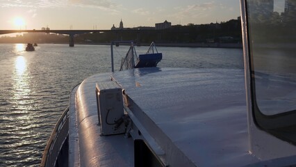 Bow of passenger ferry moving on river at sunset near city. Clip