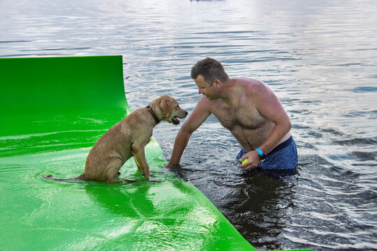 Man standing in water with a dog on a raft
