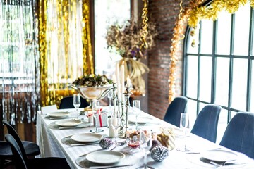 Elegant dining table set for a festive Christmas celebration with white tablecloth, candles, and decorations. Bright, festive, and inviting atmosphere for a Christmas celebration.