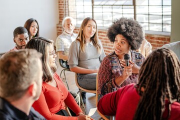 African American woman speaking in diverse business seminar. Diverse group of people audience sit...
