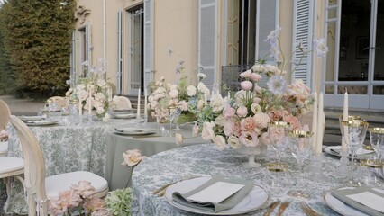 Elegant wedding reception table setting with floral centerpiece in a villa garden. Action