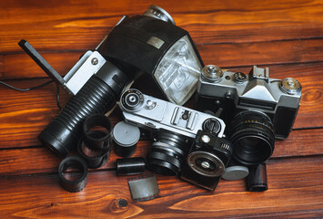 A set of vintage photographic equipment. Camera, flash, film and exposure meter on a wooden...