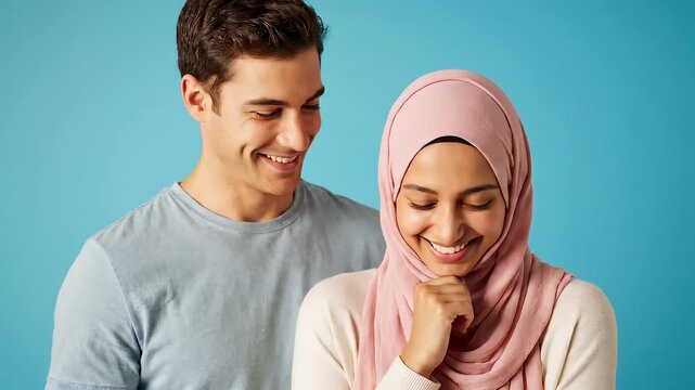 A smiling couple, a man in a gray shirt gazing at a woman wearing a pink headscarf