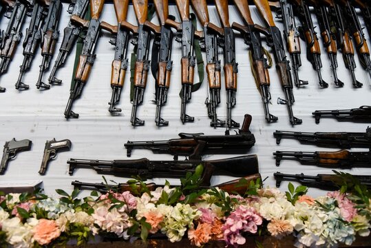 A display of surrendered weapons, including rifles others, laid out on a table