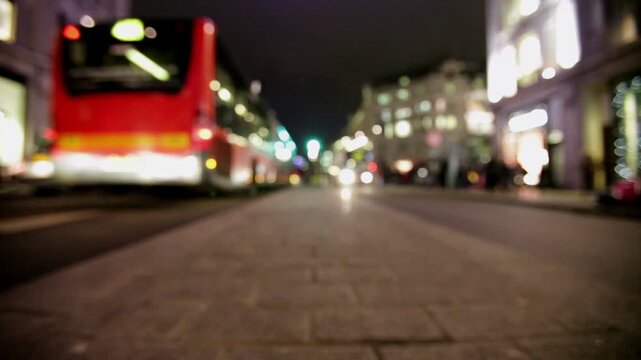Abstract, defocussed low angle view of Oxford Street, London, at night. A classic red London bus passes creating a sense of motion and urban life during late the night Christmas shopping period.