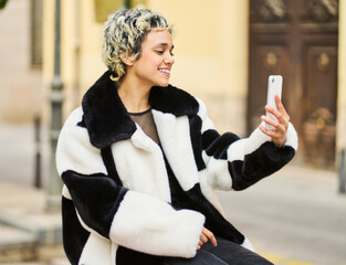 Young woman taking selfie with smartphone in city