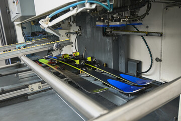 Skis moving through an automatic waxing machine, preparing for winter sports season