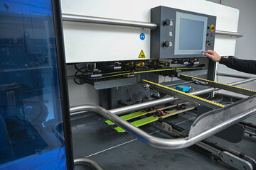 Worker operating a modern automatic machine processing skis in a factory