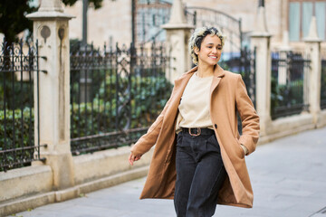 Obraz premium Woman walking city street smiling wearing coat