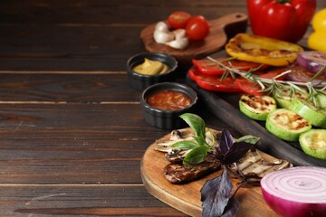 Vegetarian barbeque. Tasty grilled vegetables served on wooden table, closeup. Space for text
