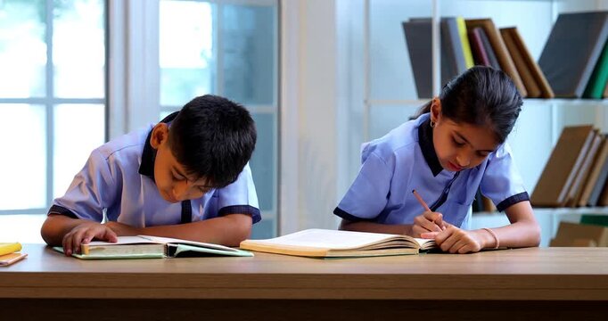 Indian School Kids Sharing Gossip with Friend in a Classroom While Wearing School Uniforms, Whispering Secret Conversations and Laughing Quietly During Leisure Moment Between Study Sessions in school