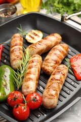 Pan with grilled sausages, vegetables and spices on table, closeup