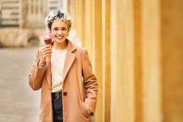 Fototapeta premium Young woman enjoying ice cream on city street