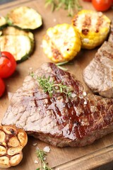 Delicious grilled beef steak with microgreens and vegetables on wooden board, closeup