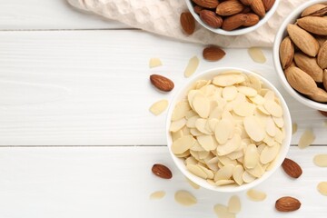 Fresh almond flakes and whole nuts on white wooden table, top view. Space for text