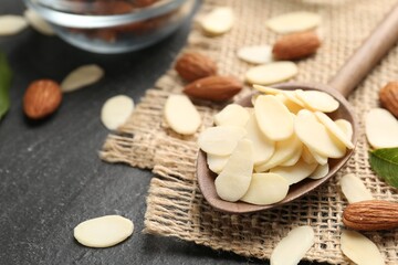 Fresh almond flakes and whole nuts on grey table, closeup