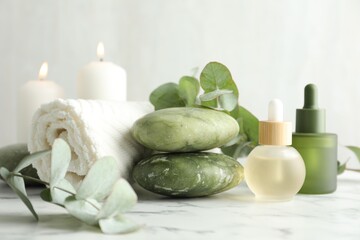 Beautiful spa composition with essential oils and eucalyptus on white marble table, closeup