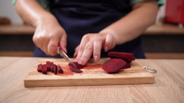 Close-up of Woman hands cutting fresh beetroot on wooden board