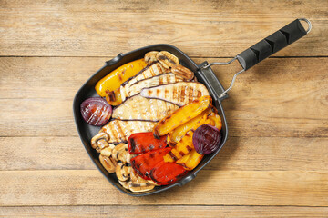 Tasty grilled vegetables and mushrooms in pan on wooden table, top view