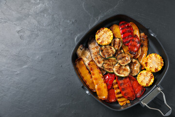 Delicious grilled vegetables in pan on dark textured table, top view. Space for text