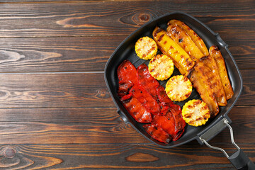 Delicious grilled vegetables in pan on wooden table, top view. Space for text