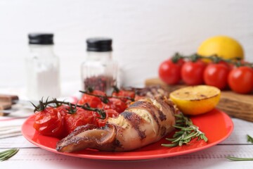 Tasty stuffed squid, rosemary, lemon and tomatoes on light wooden table, closeup