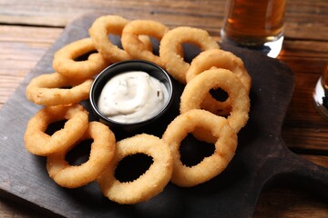 Fried squid rings with sauce and beer served on wooden table, closeup