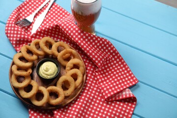 Fried squid rings with sauce and beer served on blue wooden table, above view. Space for text