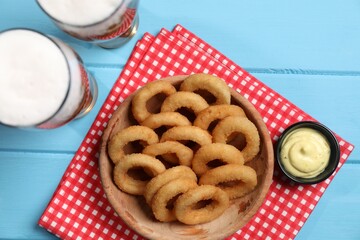 Fried squid rings with sauce and beer served on blue wooden table, flat lay