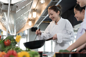 Cooking, Kitchen. Group of young female chef wearing white apron and learning cooking in kitchen at restaurant