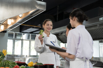 Cooking, Kitchen. Group of young female chef wearing white apron and learning cooking in kitchen at restaurant