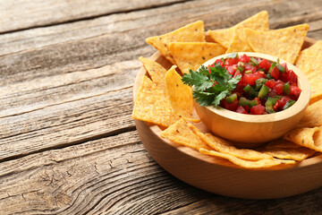 Tasty salsa with nachos on wooden table, closeup. Space for text