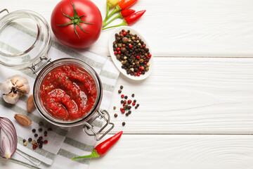 Tasty salsa sauce in jar and ingredients on white wooden table, flat lay. Space for text