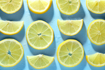 Fototapeta premium Slices of lemon and water drops on light blue background, flat lay