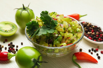 Tasty salsa in bowl and ingredients on white wooden table, closeup