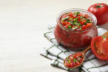 Tasty salsa in jar and ingredients on white wooden table, closeup. Space for text