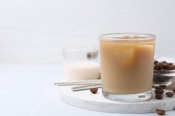 Tasty iced coffee with milk and beans on white table. Space for text