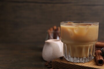 Tasty iced coffee with milk and beans on wooden table. Space for text